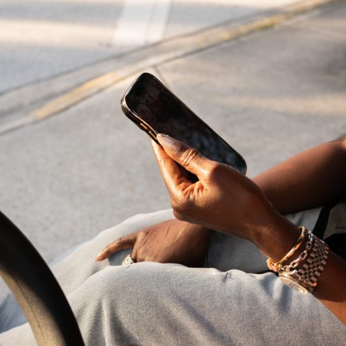 close up of a woman's hands holding a phone while sitting outside on a golf cart